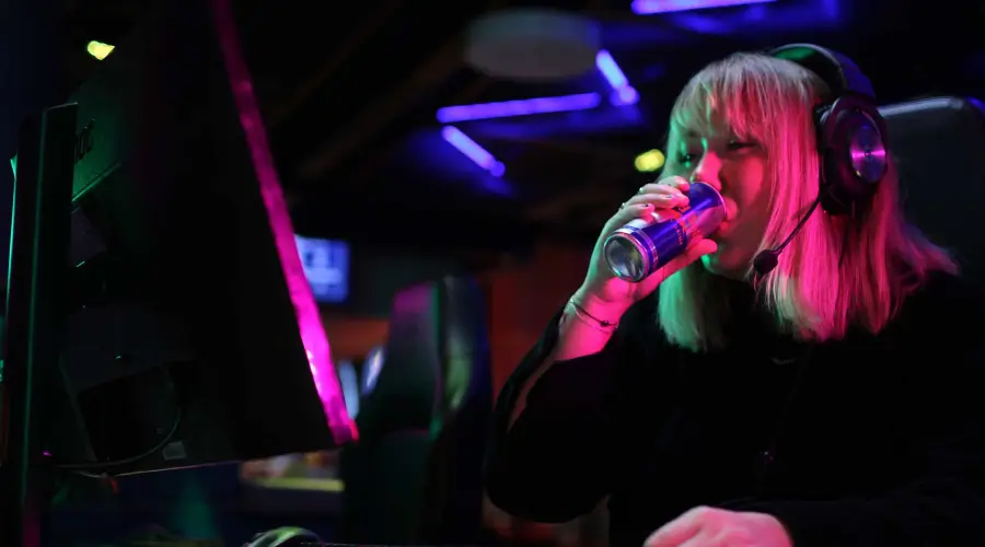 En kvinna som dricker ur en burk när hon spelar på Inferno Online